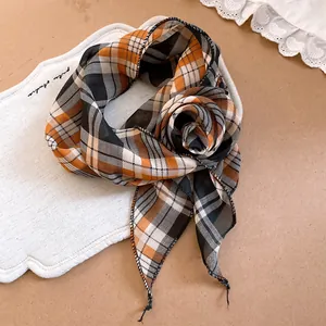 Detailaufnahme eines orange-schwarz karierten Schals im Maillard-Stil, geformt als Blume