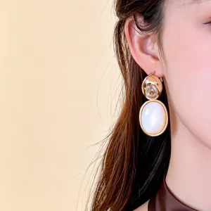 Gros plan sur des boucles d'oreilles clips en or 18 carats avec zircon et nacre porté