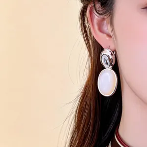 Gros plan d'une boucle d'oreille plaquée or 18 carats avec zircon et nacre ovale.