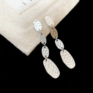 Vue rapprochée des boucles d'oreilles argentées avec des disques ovales au fini martelé