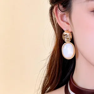 Vue détaillée des boucles d'oreilles pendantes ovales en zircon et nacre plaqué or 18k