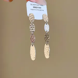 Gros plan montrant la texture plissée des boucles d'oreilles à maillons ovales