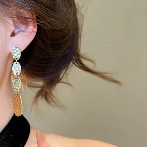 Détail de boucles d'oreilles pendantes ovales en métal texturé portées par un mannequin