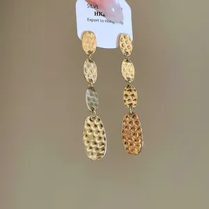 Gros plan sur les boucles d'oreilles ovales étagées dorées à texture martelée chic