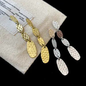 Détail des boucles d'oreilles pendantes ovales martelées en finitions dorée et argentée