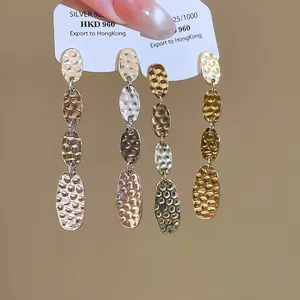 Vue macro montrant la texture plissée et la forme ovale de ces boucles d'oreilles.