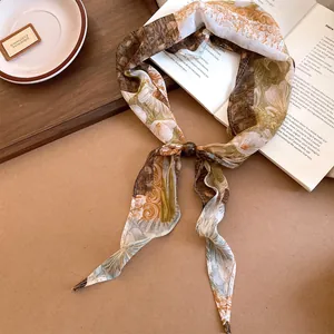 Détail rapproché d'un foulard en soie vintage à fleurs avec perles et tons terre.