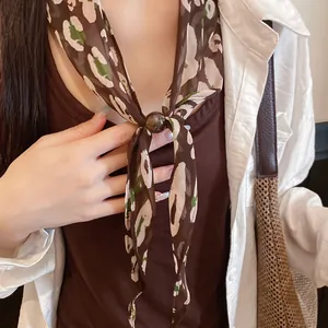 Gros plan d'un foulard en soie léopard vintage avec un fermoir en perle marron ronde