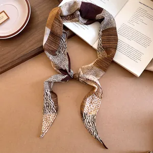 Détail d'un foulard fin en soie à imprimé animal avec perle décorative brun terre.