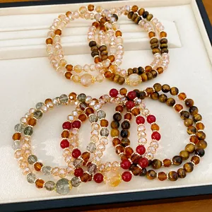 Vista detallada de elegantes pulseras de ojo de tigre y cuentas de vidrio en capas
