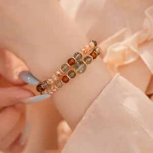 Primer plano de pulseras de capas con ojo de tigre y cuentas de vidrio en la muñeca femenina