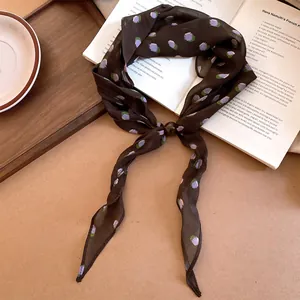 Gros plan d'un foulard en soie marron à fleurs avec perle foncée.