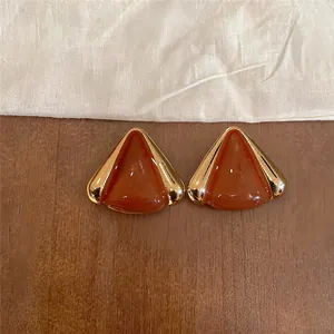 Vista detallada de aretes triangulares de gota de aceite con elegantes bordes dorados