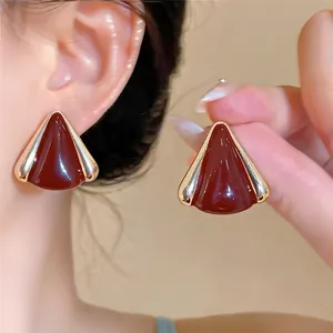Vista detallada de elegantes pendientes triangulares de esmalte granate con borde dorado