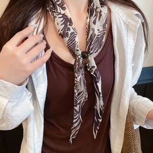 Gros plan d'un foulard en soie vintage à motif floral avec un fermoir en perle noire élégant