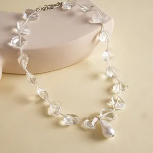 Close-up of a minimalist necklace featuring clear glass beads and a white pearl pendant