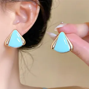 Primer plano de los pendientes triangulares de esmalte azul claro con bordes dorados