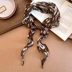 Gros plan d'un foulard en soie vintage à motif floral avec une perle décorative élégante