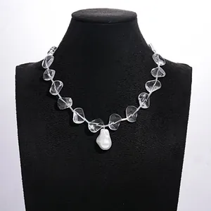 Clear glass bead necklace with a white baroque pearl pendant on a black mannequin