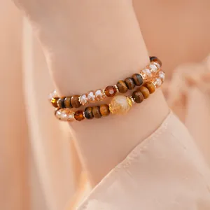 Primer plano de pulsera de cuentas en capas con ojo de tigre y cuentas de vidrio en muñeca