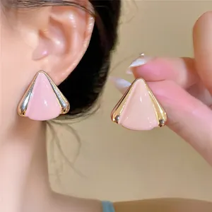 Vista detallada de elegantes pendientes triangulares de esmalte rosa con borde dorado