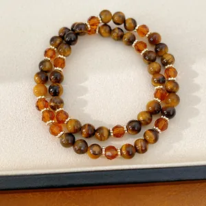 Primer plano de pulseras de cuentas estilo Maillard con ojo de tigre y vidrio ámbarado