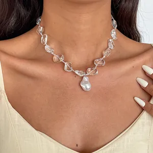 Close-up view of elegant clear glass bead necklace featuring a baroque pearl pendant