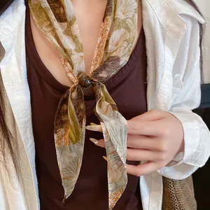 Vue détaillée d'un foulard léger rétro à fleurs avec un accent perlé sur modèle.