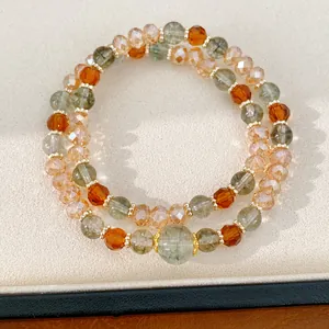 Detalle de una pulsera de doble capa con cuentas de vidrio facetadas en color ámbar y verde.