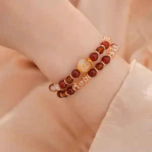 Primer plano de pulseras de cuentas apiladas con tonos cálidos de ámbar y rojo