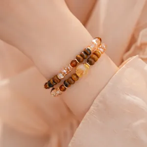 Vista detallada de elegantes pulseras en capas de ojo de tigre y cuentas de vidrio