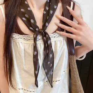 Gros plan d'un foulard en soie marron vintage à fleurs avec un joli détail de perle