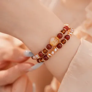 Detalle de pulsera de cuentas en capas con piedras rojas y ámbar en la muñeca
