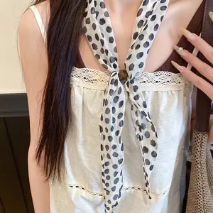Vue rapprochée d'un foulard en soie vintage à pois avec un curseur décoratif en perle.