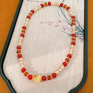 Vista detallada de una pulsera de cuentas rojas y ámbar con piedra ojo de tigre