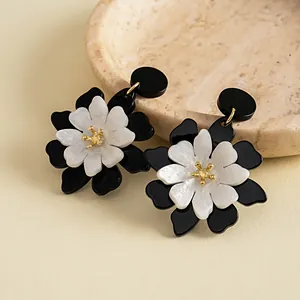 Primer plano detallado de elegantes pendientes de flores de acrílico en blanco y negro