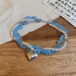 Vue détaillée d'un collier multicouche avec pierres bleues, perles et pendentif cœur.
