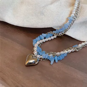 Vue détaillée du collier multicouche avec perles, pierres bleues et pendentif cœur.