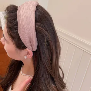 Λεπτομερής προβολή μιας κομψής ροζ πλισέ υφασμάτινης στέκας σε μακριά καστανά μαλλιά