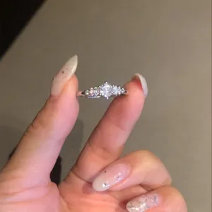 Detailweergave van een Franse luxe ronde zirkonia ring vastgehouden tussen vingers.