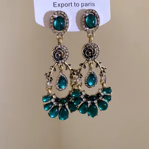 Détail de boucles d'oreilles vintage de style palais avec résine émeraude et strass