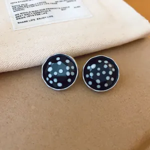 Detailopname van retro ronde oorknopjes met zwart-witte stippen en zilveren randen