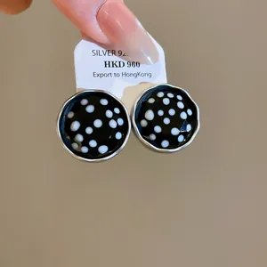 Detailopname van vintage ronde oorknopjes met zwarte en witte stippen op een kaartje