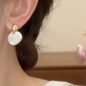 Primer plano de un elegante pendiente redondo minimalista francés en la oreja de la modelo.