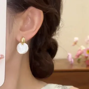Primer plano de pendientes redondos de estilo francés con acabado en oro y blanco esmaltado.