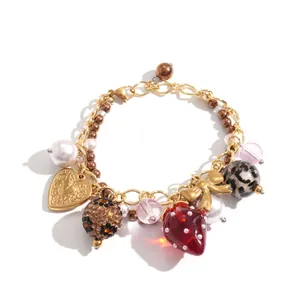 Handgemaakte bedelarmband met aardbei van hars, gouden hart en parelhangers.