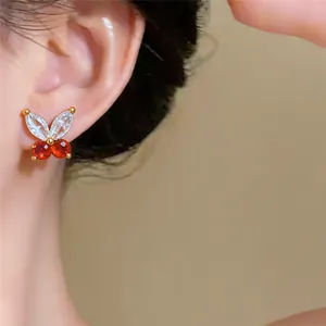 Detailaufnahme von Schmetterling-Ohrsteckern mit roten und weißen Zirkonia-Steinen.
