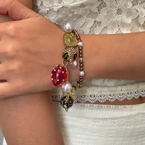 Detailopname van luxe bedelarmband met hars aardbei, parels en een gouden hartje