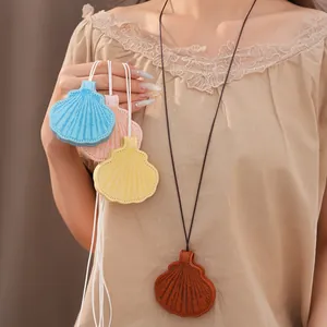 Detail showing colorful shell-shaped leather necklaces styled on a beige lace top