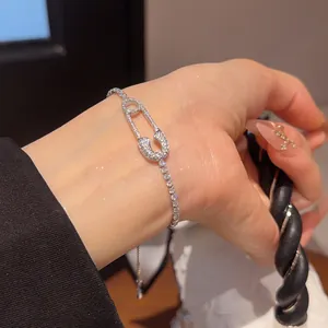 Primer plano de una pulsera de lujo con forma de imperdible y circonitas en la muñeca.